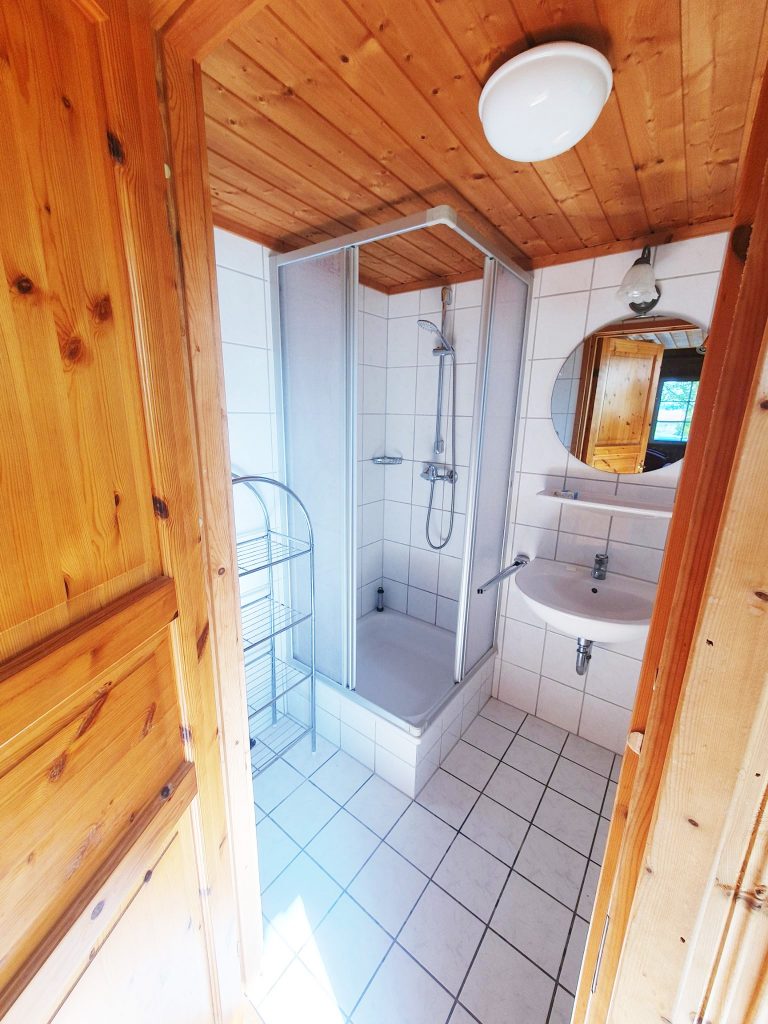 Innenaufnahme vom Ferienhaus Seebrise, Bad mit Dusche und Waschbecken mit Spiegel und Beleuchtung.