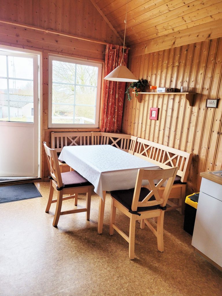 Innenaufnahme vom Ferienhaus Seebrise mit Sitzecke, bestehend aus Esstisch, einer Eckbank und zwei Stühlen.