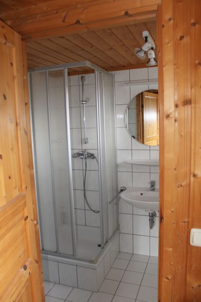 Innenaufnahme vom Ferienhaus Kormoran in Userin, darauf zu sehen Bad mit Eckdusche und Waschbecken mit Spiegel.  