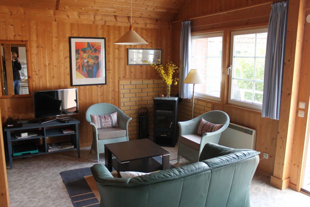 Innenaufnahme vom Ferienhaus Kormoran mit Couch, Sesseln und Kaminofen.  