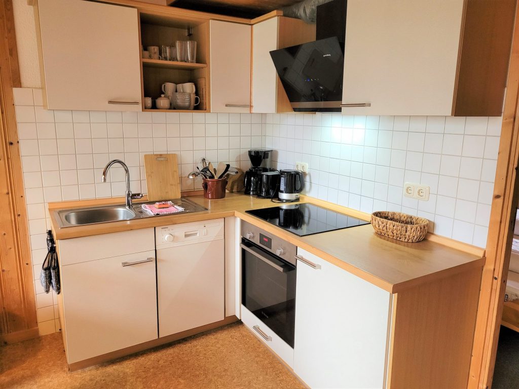 Innenaufnahme vom Ferienhaus Kormoran mit voll ausgestatteter Küchenzeile inclusive Geschirrspüler, Ceran-Kochfeld und Backofen.