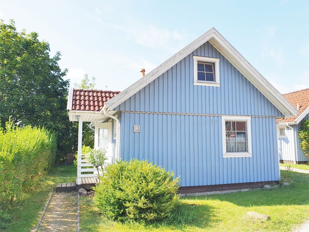 Nordansicht von Haus Seebrise am Useriner See, ein blaues Ferienhaus aus Holz im skandinavischen Stil.