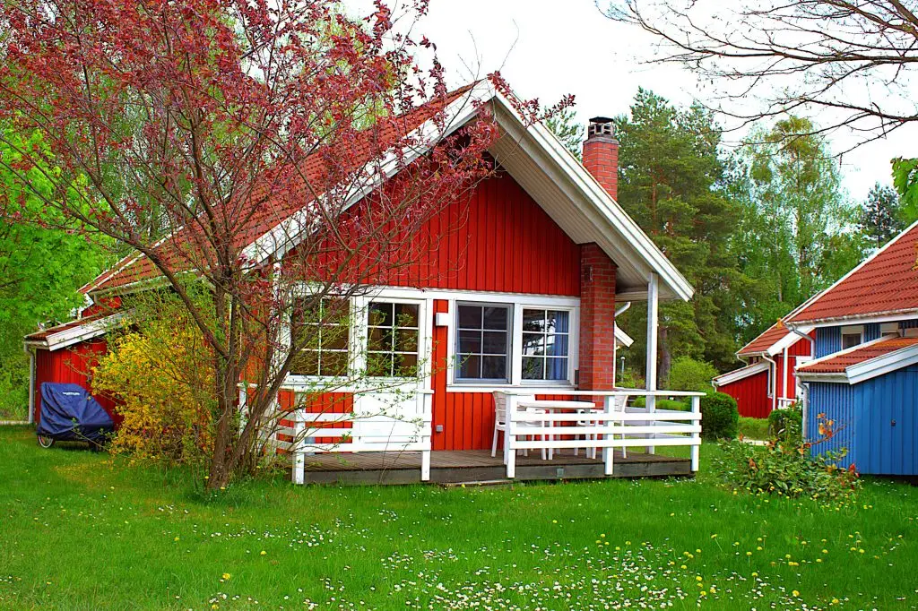 Rotes Ferienhaus Kormoran am Useriner See im skandinavischen Stil aus Holz gebaut mit Terrasse für den Urlaub.  