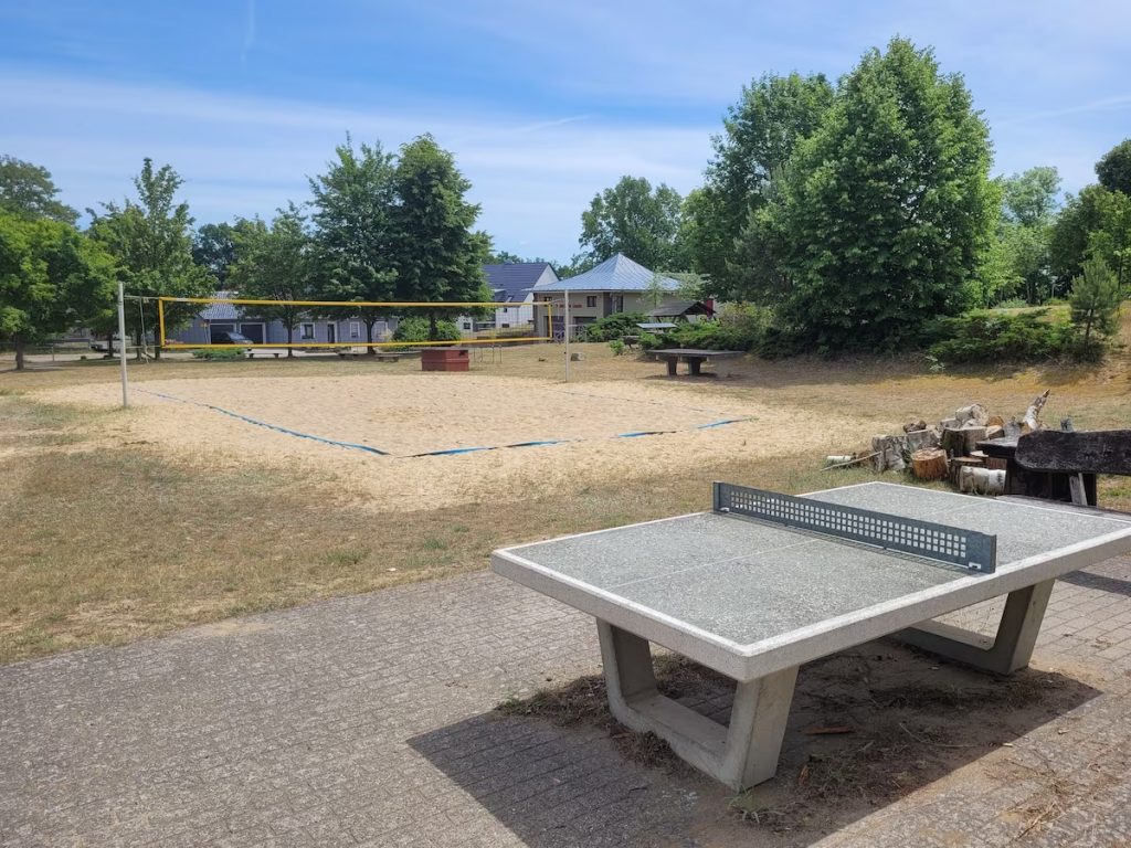 Volleyballplatz und Tischtennisplatte auf dem Sportplatz am Ferienzentrum Useriner See, wo Ferienhäuser vermietet werden.  