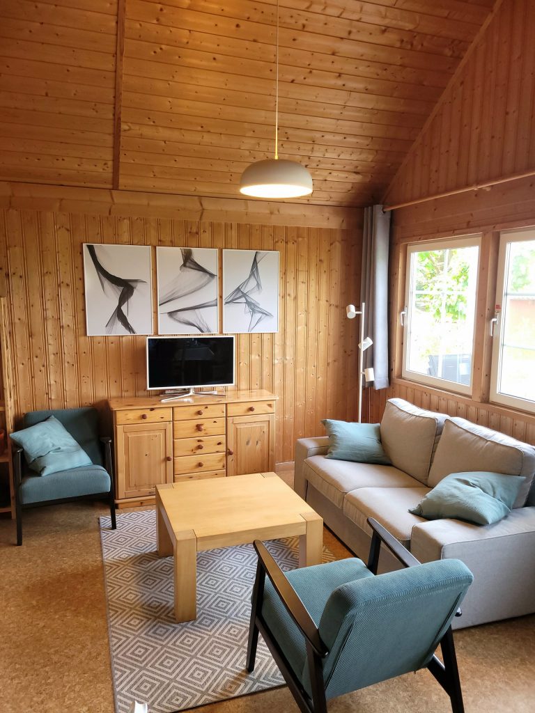 Innenaufnahme vom Ferienhaus Seebrise am Useriner See mit Couch, Sesseln und LED-Fernseher.