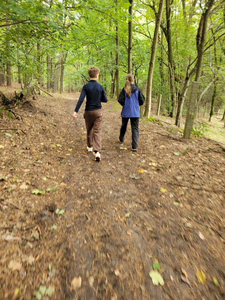 Zwei Kinder laufen auf einem Waldweg.